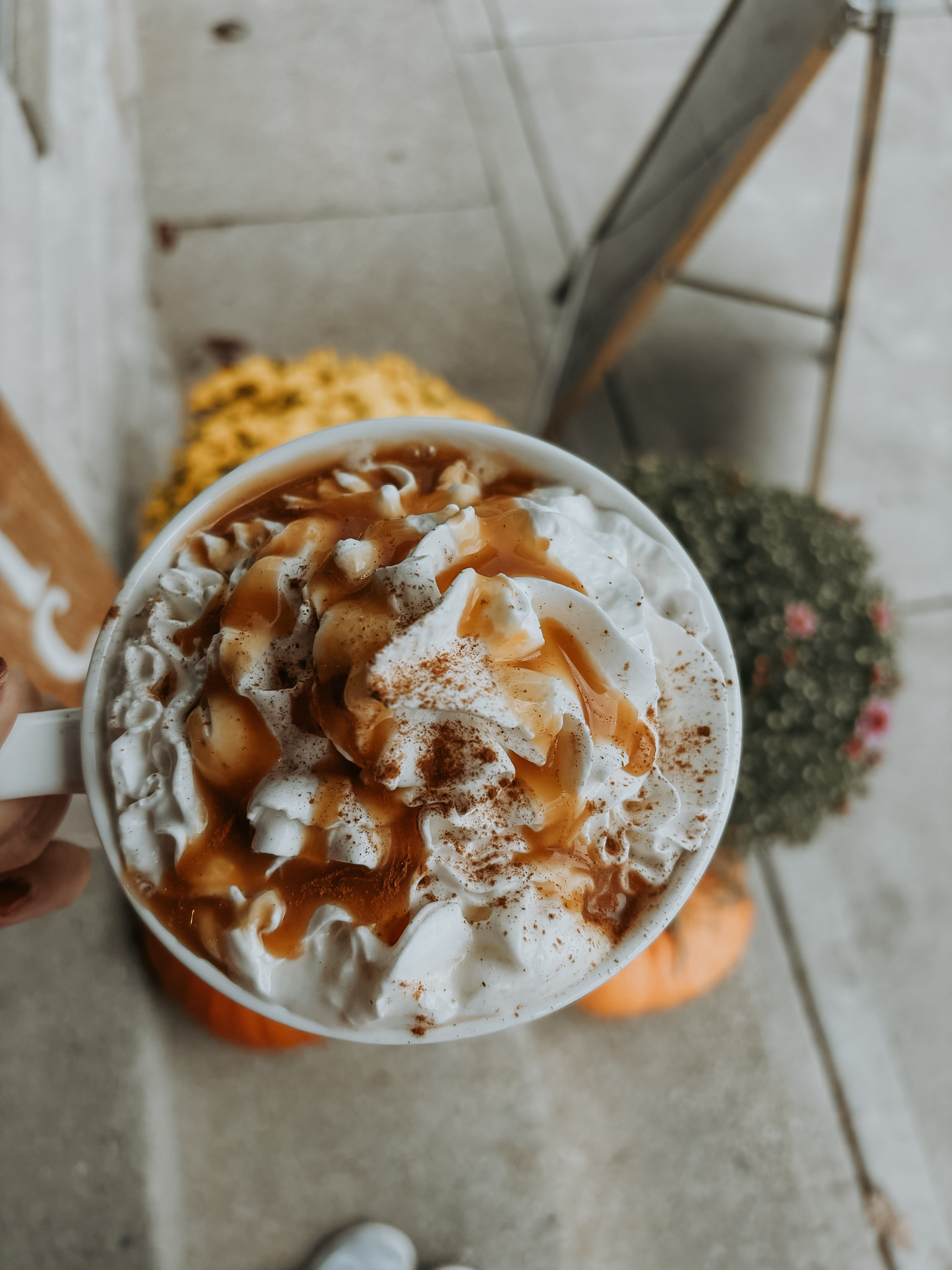 A mug piled with whipped cream, caramel and cinnamon