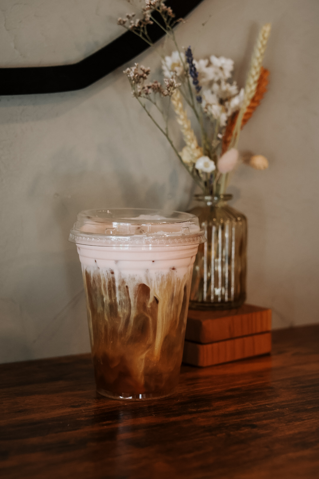 Iced latte with pink cold foam and dried flowers
