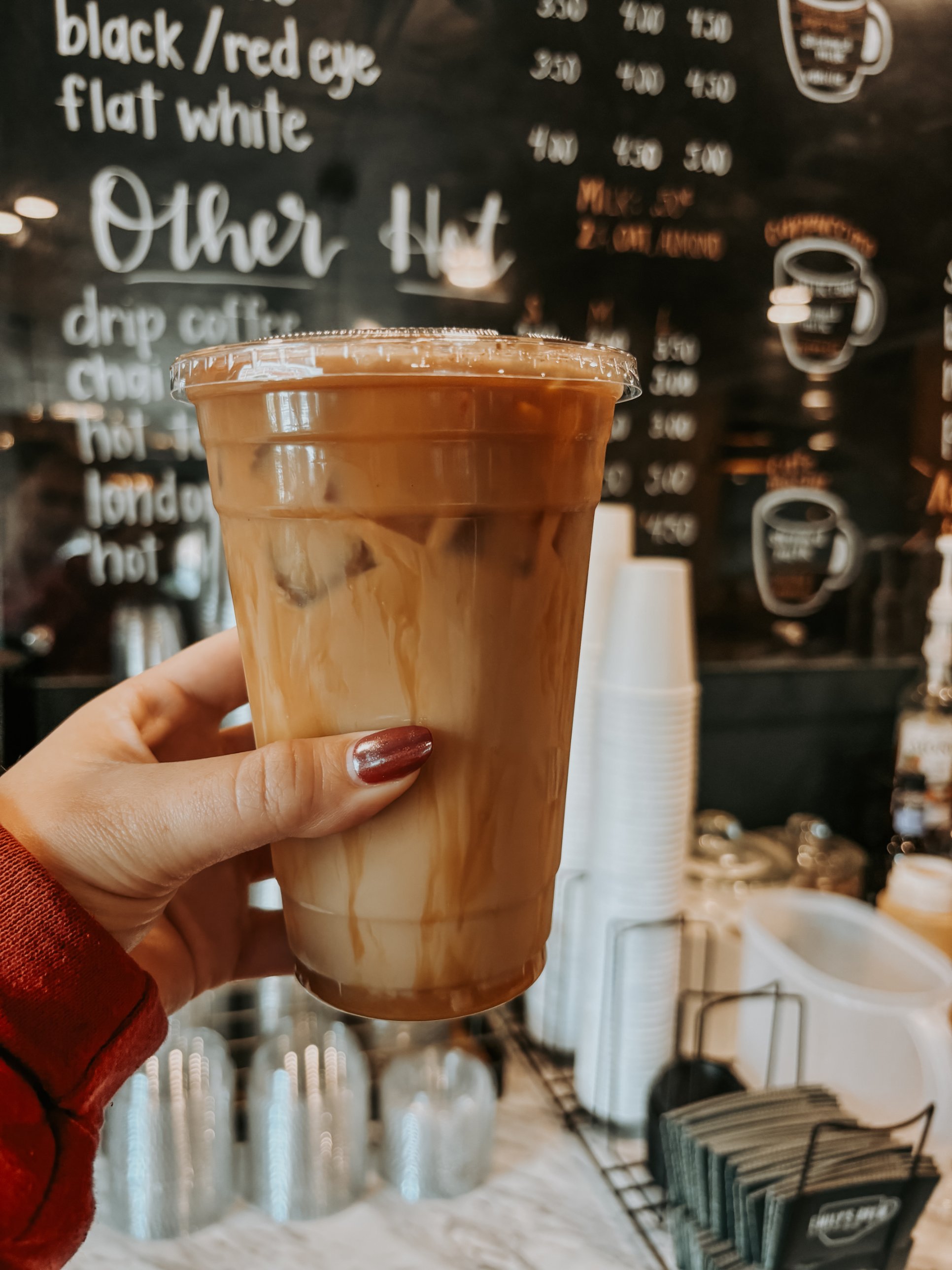 An iced latte in front of the handwritten menu board
